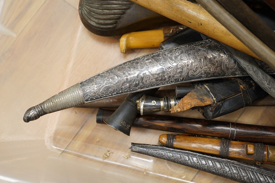 Eighteen assorted world weapons comprising a silver jambya (pommel missing), a knobkerry, a dha, two kris (one with handle missing), a lohar, three kukris, a djambok, a Chinese trousse, a chora, a flyssa, five others and
